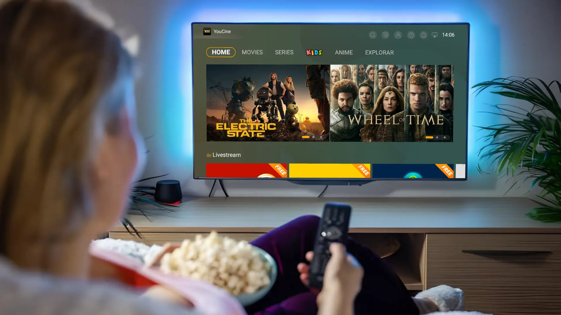 A girl sitting on a couch, watching a movie on the Youcine, with popcorn beside her and a television in view.